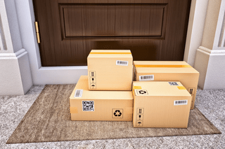 Pile of packages delivered on the front porch of a house.