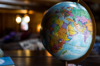 Globe on a desk with a dark blurred office background.