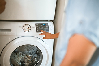 A man starting a washing machine full of clothes.