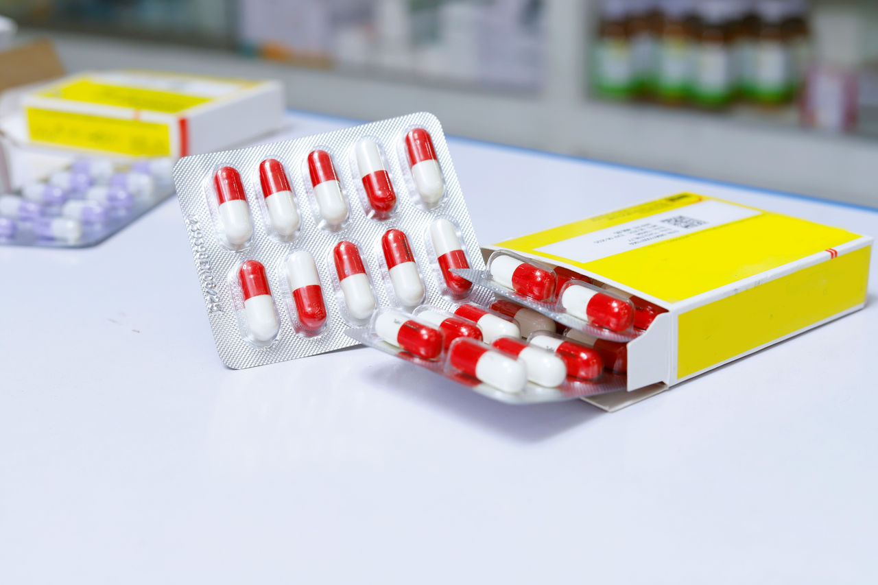 Blister packs of red-and-white capsules partially removed from a yellow-labeled box.