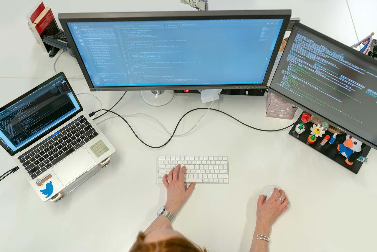 Deux employés travaillant avec une machine de moulage recouverte de graphiques issus de l’analyse d’infrastructure basée sur le cloud de Minitab.